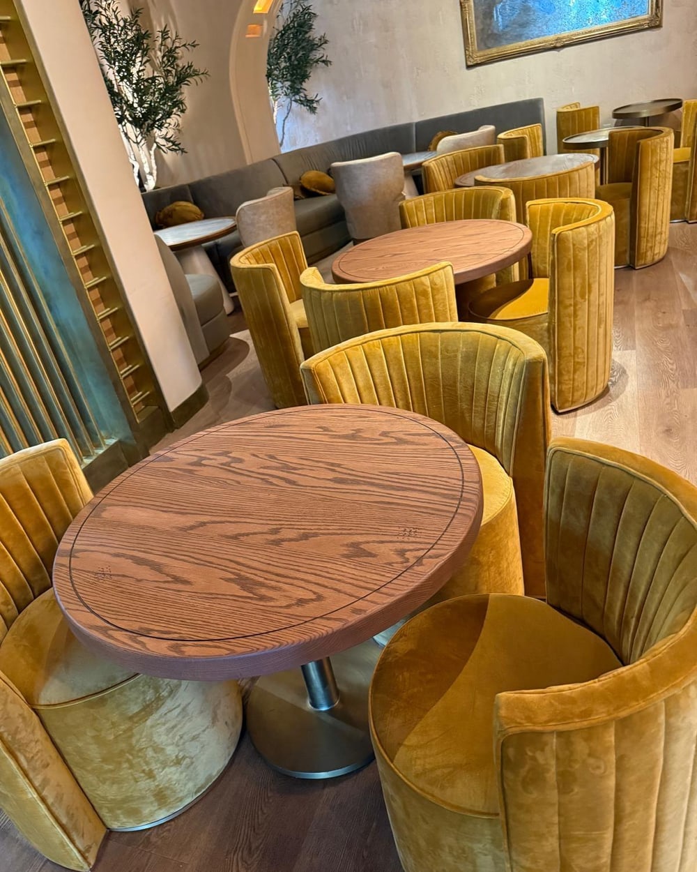 Custom mustard velvet swivel chairs and solid oak oval tables built for a lounge