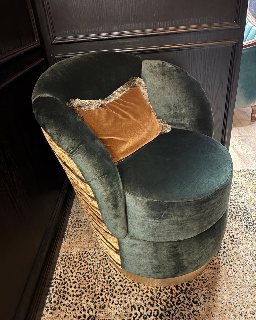 Custom green velvet swivel chair with a tiger-velvet back panel and brass plinth base